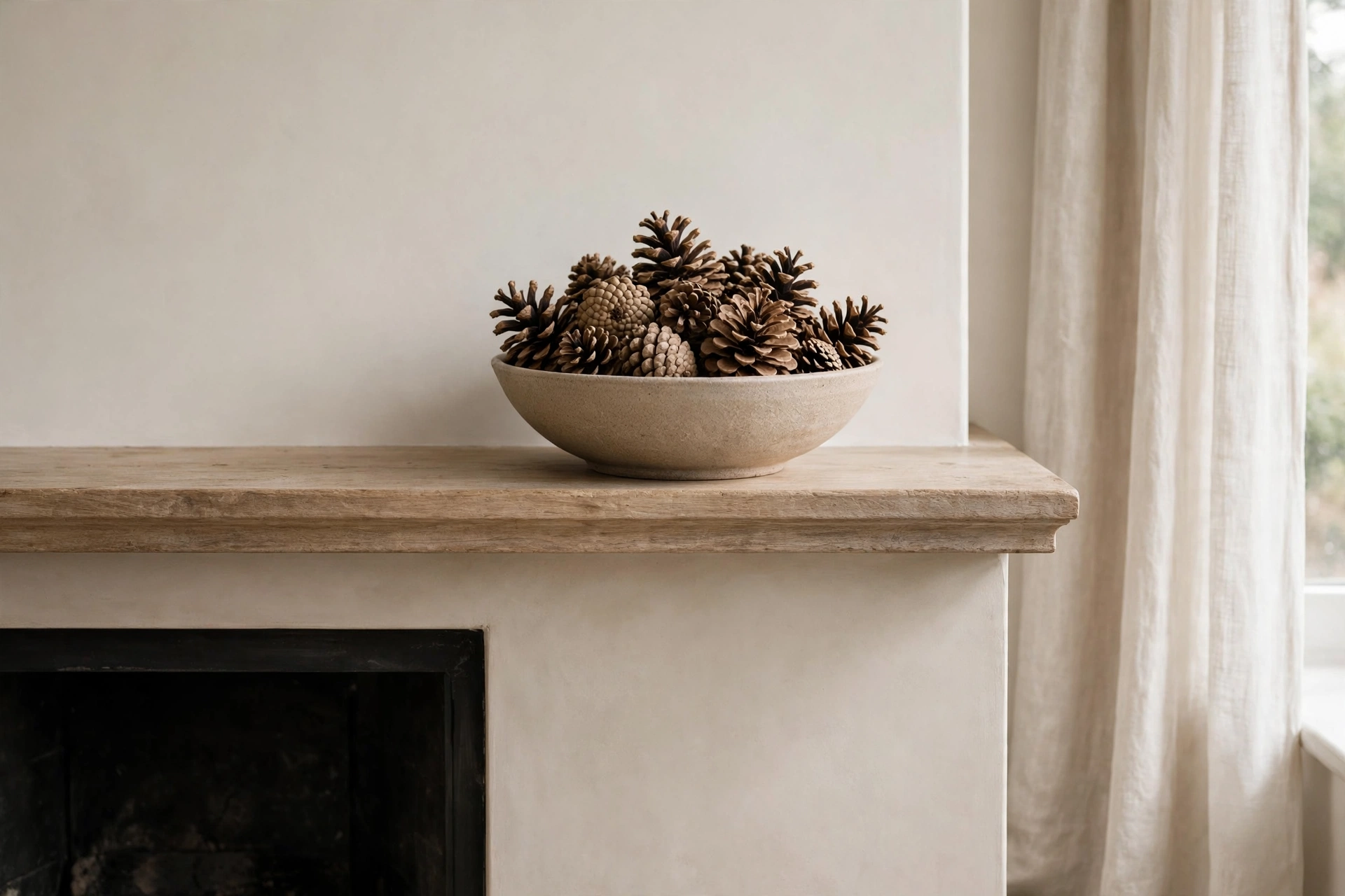 Bowl filled with pinecones adding woodland texture to a mantel.